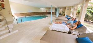 a group of people sitting on couches in front of a swimming pool at Leman Hotel y Apartamentos in Playa de Palma