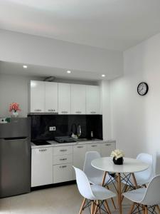 a kitchen with white cabinets and a table and chairs at Vila Topi in Vlorë +26 photos