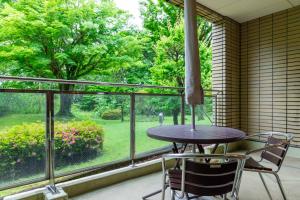 a table and chairs in front of a large window at Izukogen Hotel Itsutsuboshi in Ito