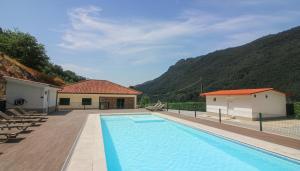 a swimming pool with a house and mountains in the background at Paraíso do Gerês in Geres