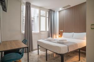 a bedroom with a bed and a table and a window at Ella Torremolinos Centro in Torremolinos