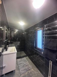 a black tiled bathroom with a sink and a window at Сузірʼя in Vorokhta +14 photos