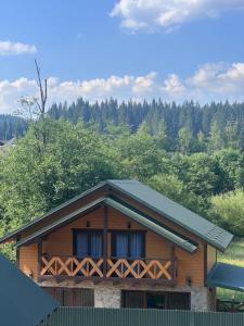 a house with a green roof with trees in the background at Сузірʼя in Vorokhta