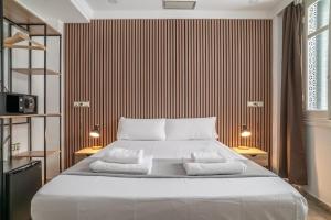 a bedroom with a large white bed with two lamps at Ella Torremolinos Centro in Torremolinos
