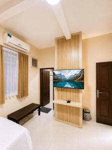 a room with a bed and a tv on a wall at Enny's Guest House in Malang