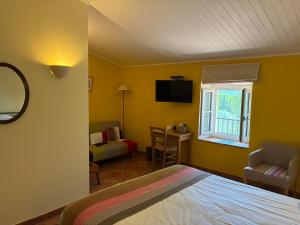 a bedroom with yellow walls and a bed and a window at Hotel Le Moulin du Château in Saint-Laurent-du-Verdon