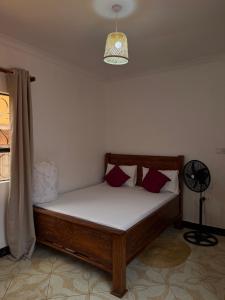 a bed in a room with a lamp and a window at Amora Homestay and Safaris in Karatu +12 photos