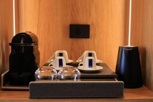 a table topped with a coffee maker and two glasses at Hotel Camelot By Artur in Ksamil