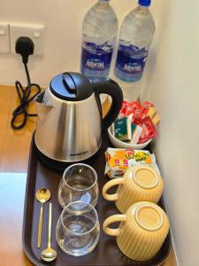 a tray with a tea kettle and cups and water bottles at Villa Nutmeg Grove Galle in Galle