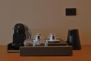a table with a coffee maker and glasses on it at Hotel Camelot By Artur in Ksamil