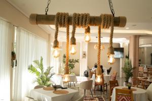 a restaurant with white tables and chairs and lights at Lùmar Hotel in Vlorë