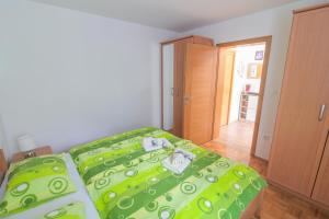 a bedroom with a bed with a green comforter at Počitniško stanovanje Aurora in Bovec