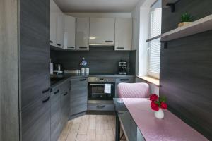 a kitchen with white cabinets and a pink chair at Počitniško stanovanje Aurora in Bovec