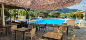 a restaurant with tables and chairs next to a pool at Achillion Hotel in Skala Potamias +17 photos