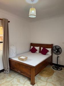 a bedroom with a bed with white sheets and red pillows at Amora Homestay and Safaris in Karatu