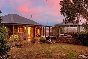 a house with a person sitting outside of it at BullerRoo Luxury Chalet & Cottage Farmstay in Barwite