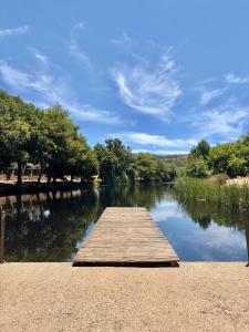 a wooden dock on a river with trees in the background at Casa Alma Clara in Odemira