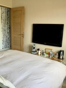 a bedroom with a white bed and a flat screen tv at Chez Marianne in Wailly
