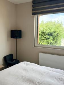 a bedroom with a bed and a window with a chair at Chez Marianne in Wailly