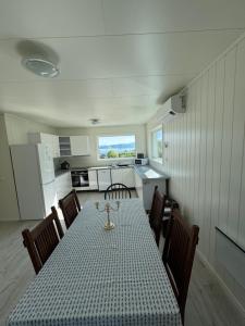 a dining room with a table and chairs and a kitchen at House on the lake in Bogen