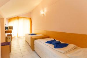 a hotel room with two beds with blue towels on them at Къща за гости ДИАМАНТ in Primorsko