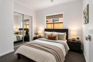 a bedroom with a large bed and two mirrors at Sara by Ready Set Stay in Caroline Springs