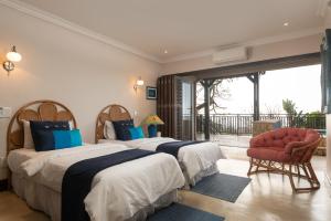 a bedroom with two beds and a chair and a window at Stella Road 24 in Ballito +25 photos
