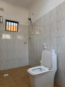 a white bathroom with a toilet and a shower at Amora Homestay and Safaris in Karatu
