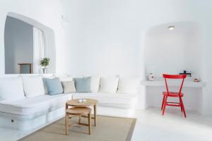 a white living room with a white couch and a red chair at Helestia Hotel, Caldera Santorini in Firostefani