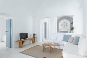 a white living room with a white couch and a tv at Helestia Hotel, Caldera Santorini in Firostefani