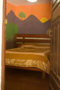 1 dormitorio con 1 cama con una pintura en la pared en Hostería - Bodega Valle Divino, en Uriondo