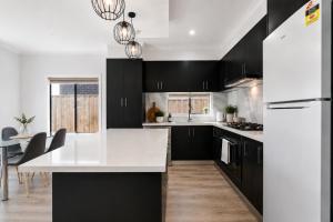 a kitchen with black cabinets and a white counter top at Sara by Ready Set Stay in Caroline Springs
