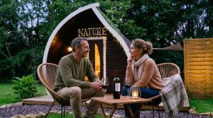 a man and woman sitting at a table in front of a tent at Little Wood Lodges in Bailly-aux-Forges