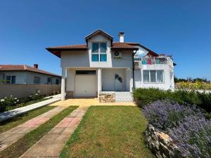 a white house with a driveway and a yard at Guest house FantasY in Tyulenovo