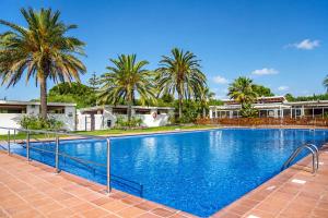 a large swimming pool with palm trees and houses at Kampaoh Cambrils in Cambrils