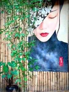 a painting of a woman on a wall with a plant at Alcove Bungalow in Hinkong