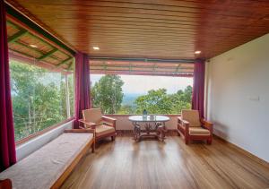 a room with a table and chairs and a large window at Celestial Heights Coorg by VOYE HOMES with Sunset views-Near to Nagarhole Tiger Reserve in Srimangala