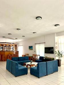 a living room with blue couches and a tv at Achillion Hotel in Skala Potamias