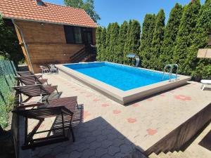 a swimming pool with chairs next to a house at Apartments Lukić in Soko Banja