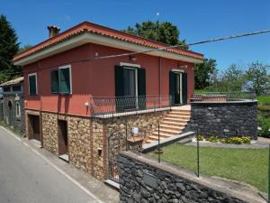 a red house with a stone wall at Villino AL CASTAGNO in SantʼAlfio