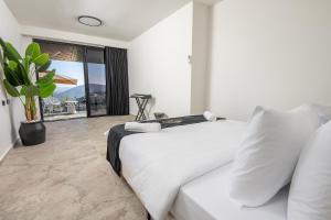 a bedroom with a white bed and a large window at כתר הגליל - ווילה יוקרתית עם 4 סוויטות ובריכה מפנקת in ‘Ein el Asad