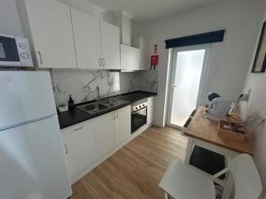a kitchen with white cabinets and a white refrigerator at Casinha da Portela in Sintra