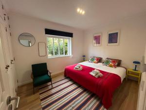 a bedroom with a bed with a red blanket and a chair at Casinha da Portela in Sintra