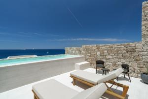 a patio with two chairs and a swimming pool at Tagoo Hills in Mikonos