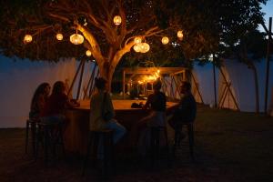 a group of people sitting at a table under a tree at Kampaoh Hostel Trafalgar in Los Caños de Meca