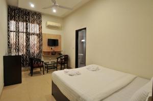 a bedroom with a bed and a table and a television at Hotel EVA in Chandīgarh