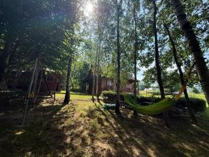 a hammock in a park with a house and trees at Drevenica U Bučkov in Lutiše