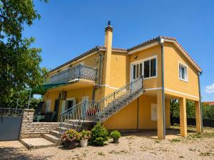 a large yellow house with a staircase in front of it at Apartment Kantun in Skradin