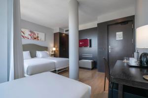 ein Hotelzimmer mit zwei Betten, einem Tisch und einem Schreibtisch in der Unterkunft Exe Moncloa in Madrid + 49 Fotos