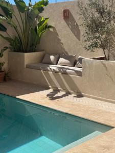 a couch is sitting next to a swimming pool at Malibu Surf House in Tamraght Ouzdar